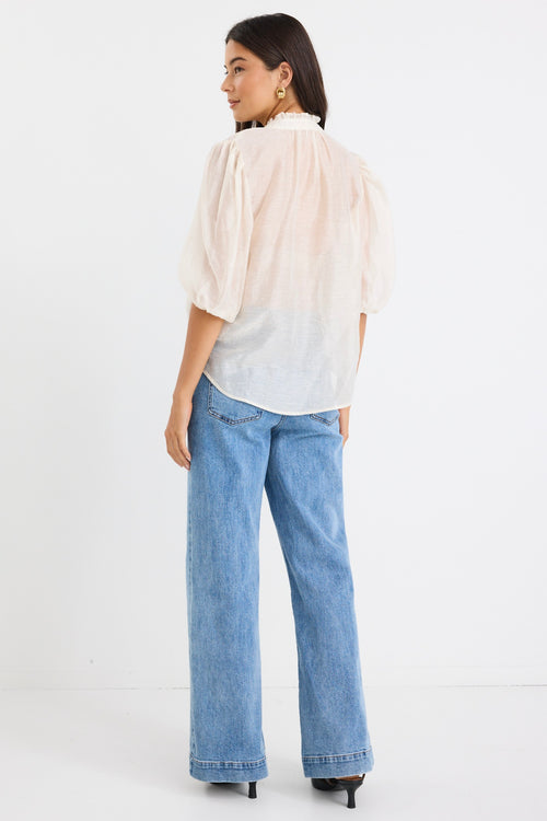 model wears a white blouse with light blue high waisted jeans