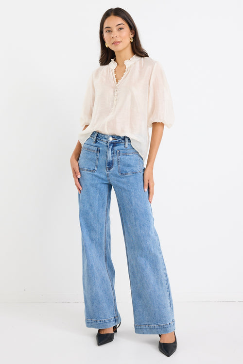 model wears a white blouse with light blue high waisted jeans