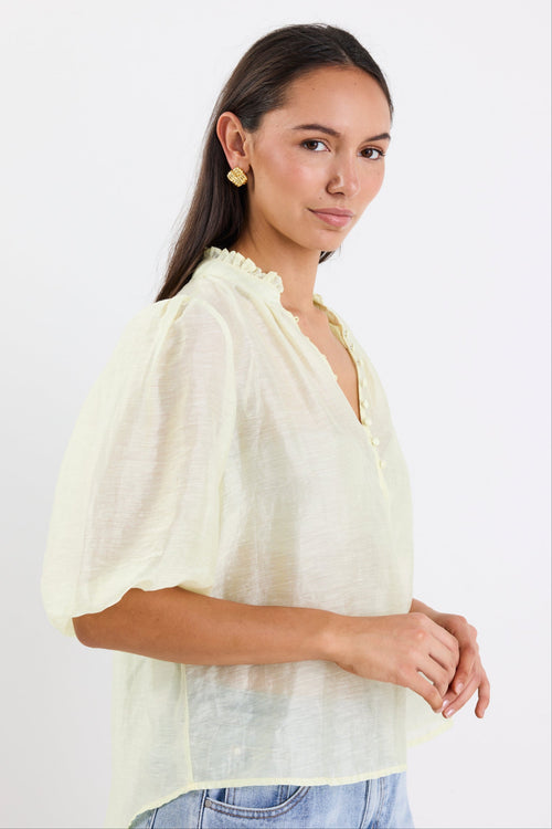 woman wearing yellow sheer blouse with blue jeans