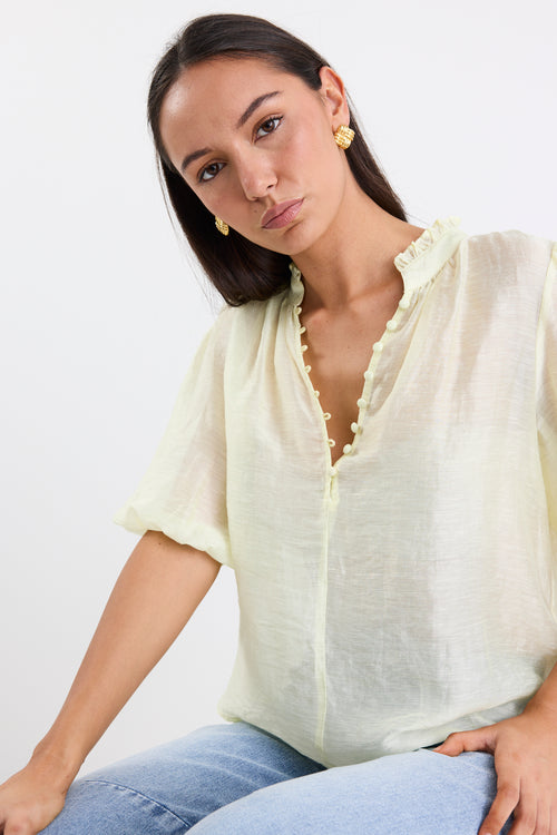 woman wearing yellow sheer blouse with blue jeans