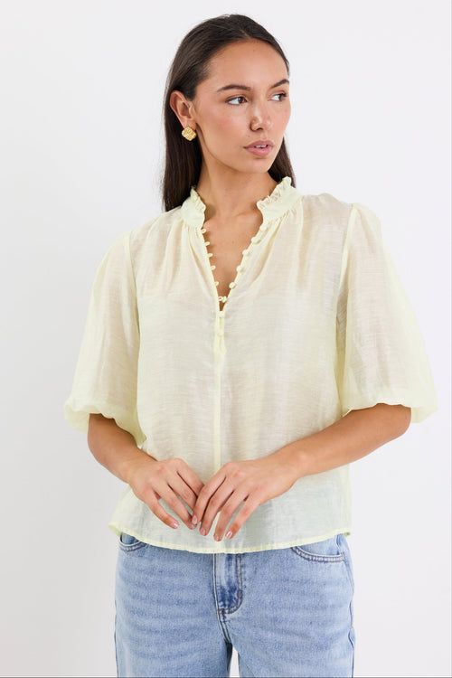 woman wearing yellow sheer blouse with blue jeans