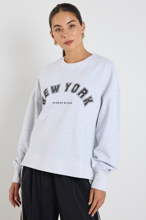 Woman wearing a light grey crew neck sweatshirt with 