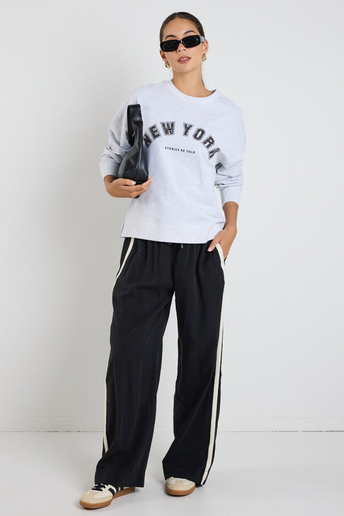 Woman wearing a light grey crew neck sweatshirt with 