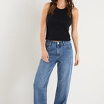 model wears a mid rise blue jean with a black tank top 