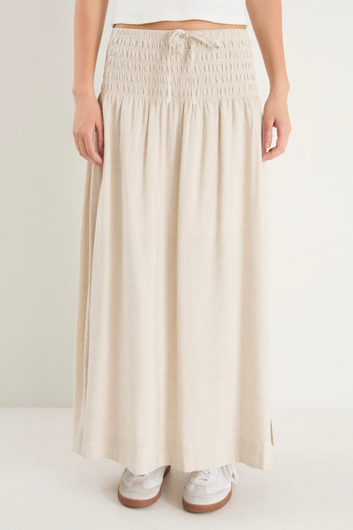 model wears a natural linen maxi skirt with a white tank top