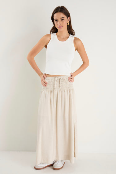 model wears a natural linen maxi skirt with a white tank top
