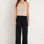 Woman wearing a beige tank top and black pants on a white background
col_pattern