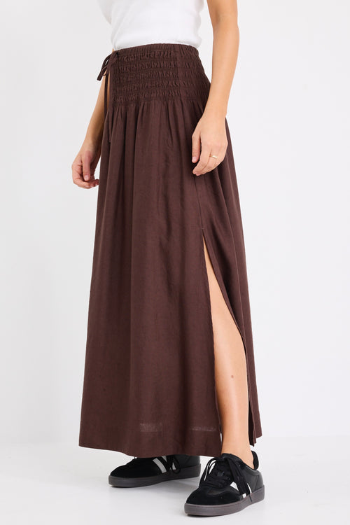 model wears a brown linen maxi skirt with a white tank top