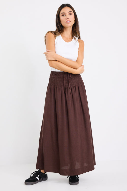 model wears a brown linen maxi skirt with a white tank top
