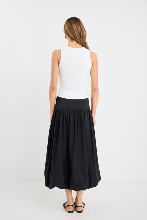 Woman wearing a white sleeveless top and black skirt on a white background