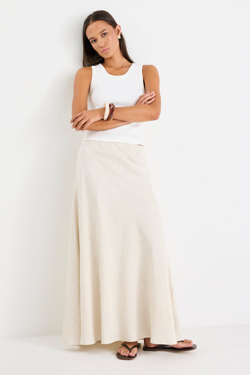 Woman wearing a maxi beige linen skirt and white tank 