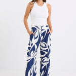 Woman wearing navy and white printed wide leg pants with an elastic waistband and high-rise fit, paired with a white tank top.