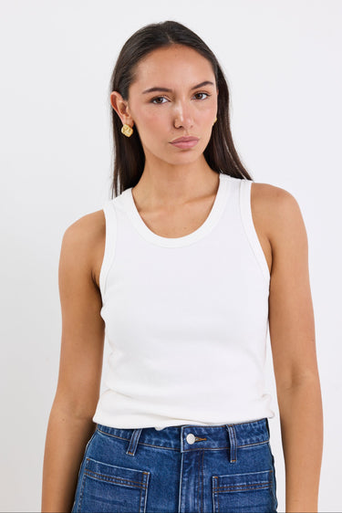 Woman wearing white sleeveless top with blue jeans