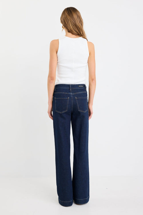 Woman wearing blue jeans and a white top on a white background