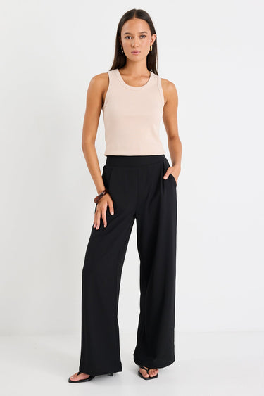 Woman wearing a black pant and beige tank