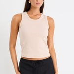 Woman wearing a beige sleeveless top and black long skirt on a white background