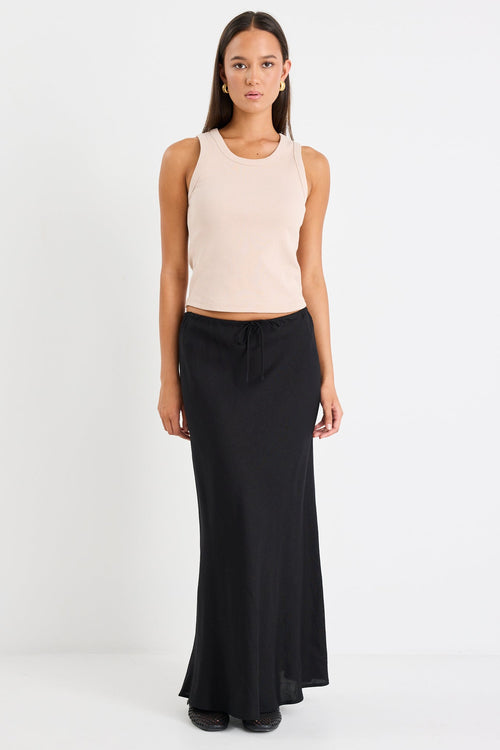 Woman wearing a beige sleeveless top and black skirt on a white background