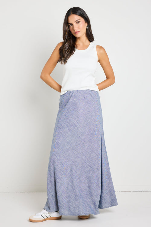 wearing a white ribbed tank top and a blue chambray maxi skirt.