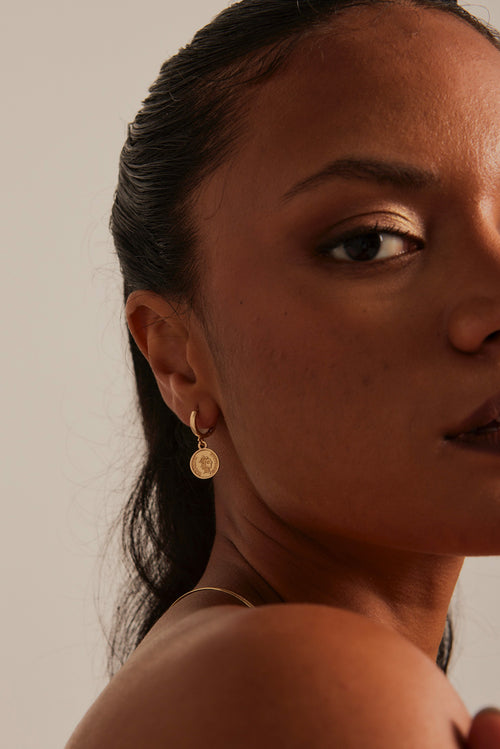 model wearing coin huggie earrings