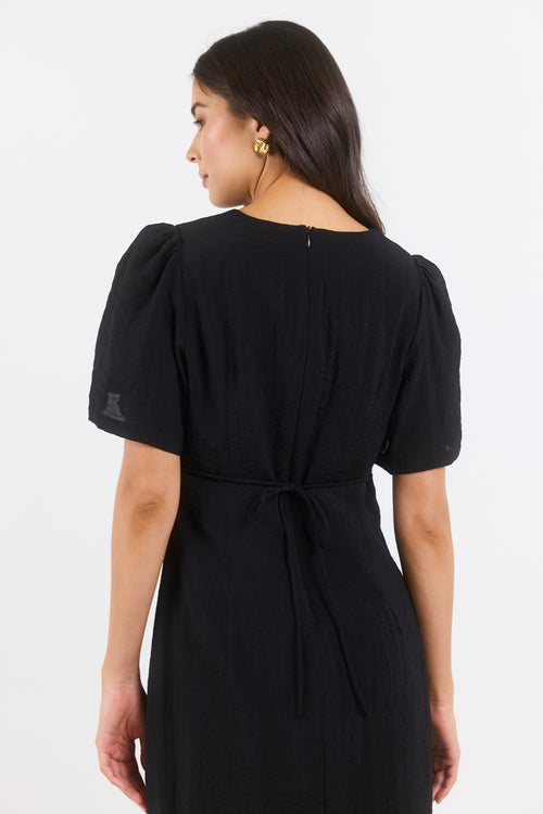 Woman wearing a black dress with puff sleeves on a white background