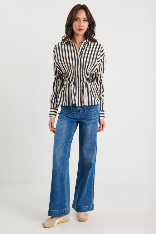 Woman wearing a striped shirt and blue jeans on a white background