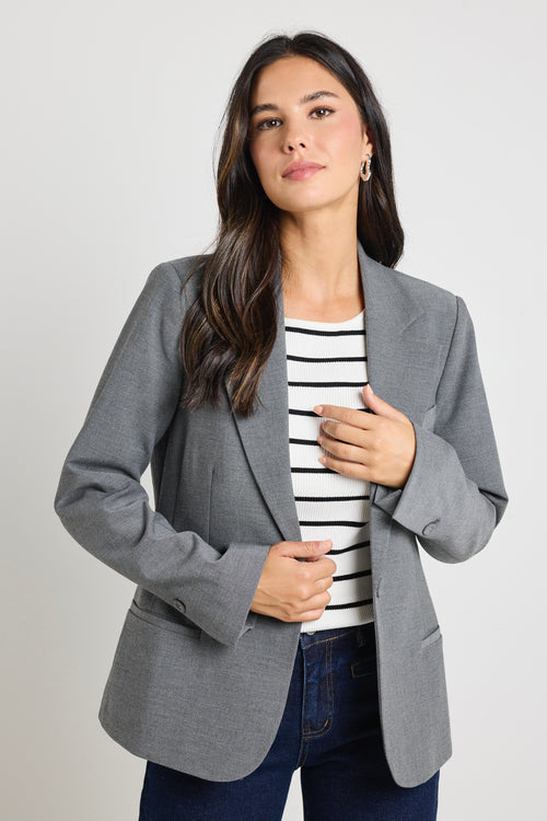 model wears grey blazer over black and white stripe top