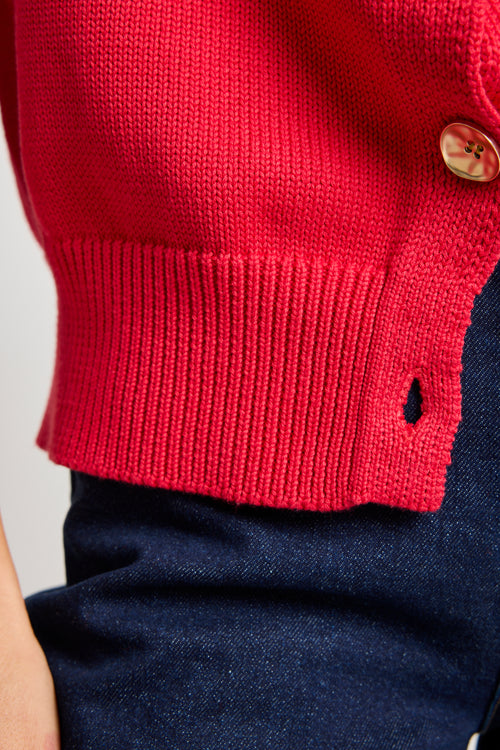 Model wears a cherry red knit vest with gold buttons. 