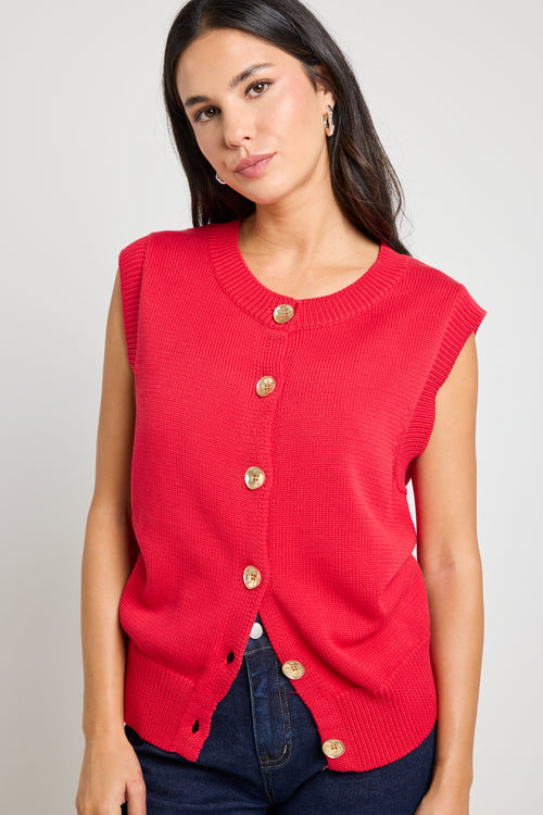 Model wears a cherry red knit vest with gold buttons. 