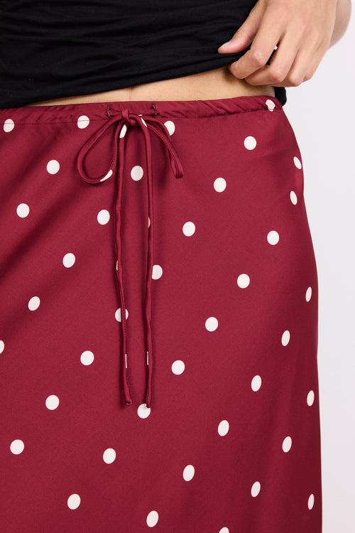 Maroon skirt with white polka dots on a plain background