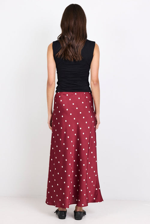 Woman wearing a black sleeveless top and red polka dot skirt on a white background