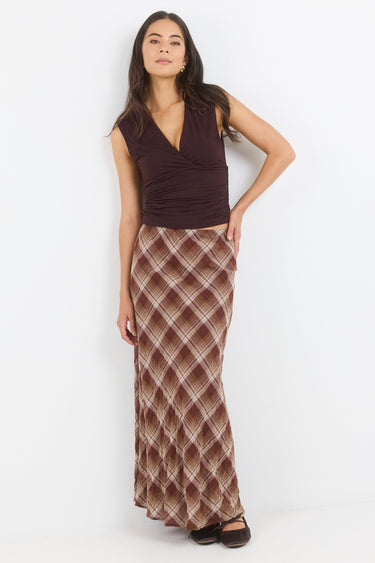 Woman wearing a brown top and patterned skirt on a white background
