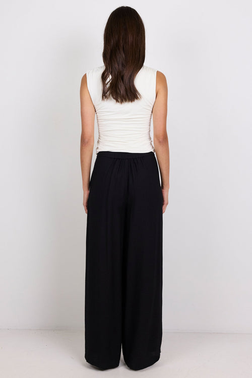 Person wearing a white top with black pants.