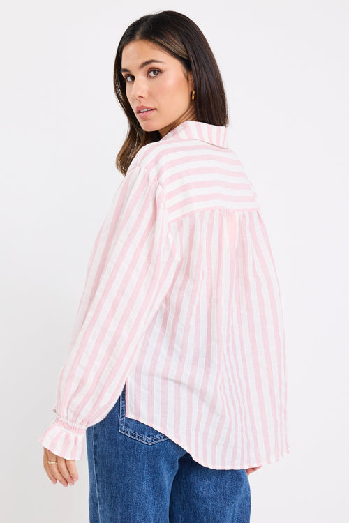 model wears a pink and white stripe shirt with dark blue jeans