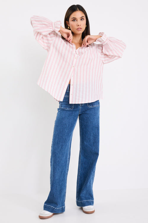 model wears a pink and white stripe shirt with dark blue jeans