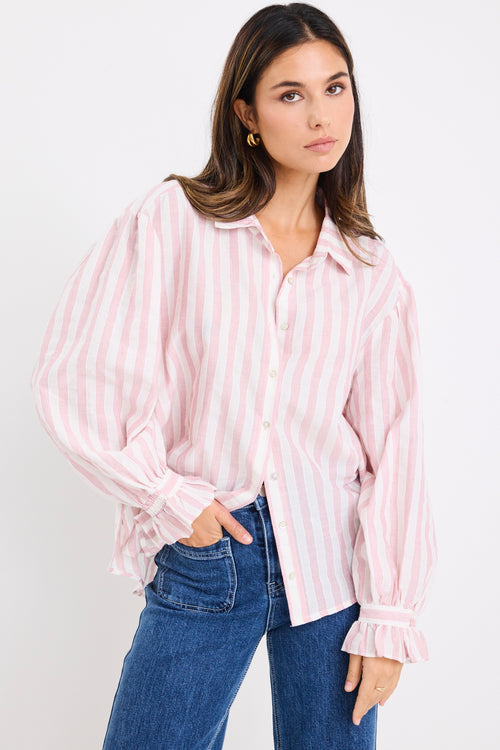 model wears a pink and white stripe shirt with dark blue jeans