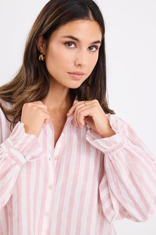 model wears a pink and white stripe shirt with dark blue jeans