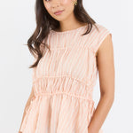 Woman wearing a peach striped top and blue jeans on a white background