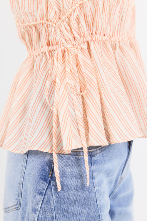 Close-up of a person wearing a peach striped top and blue jeans on a white background