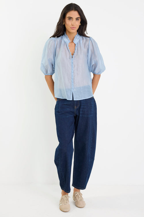 Woman wearing a light blue shirt and dark blue pants on a white background