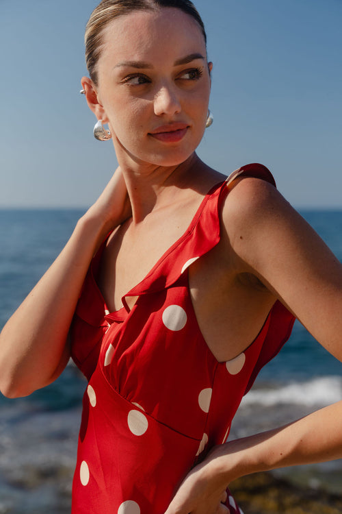 Woman in a red polka dot dress standing by the ocean