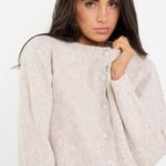 Woman wearing a beige cardigan against a white background