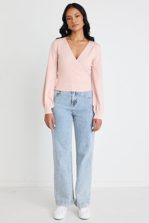 Model wears a pink wrap top with blue jeans