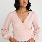 Model wears a pink wrap top with blue jeans