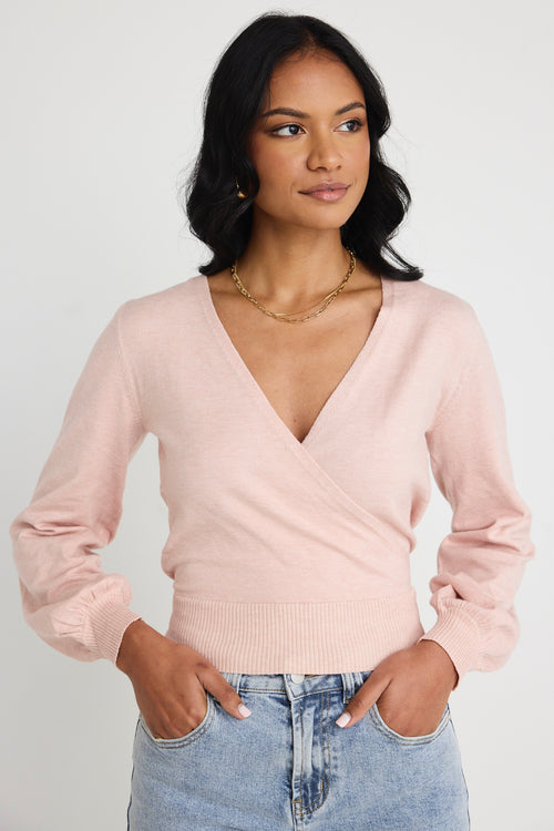 Model wears a pink wrap top with blue jeans