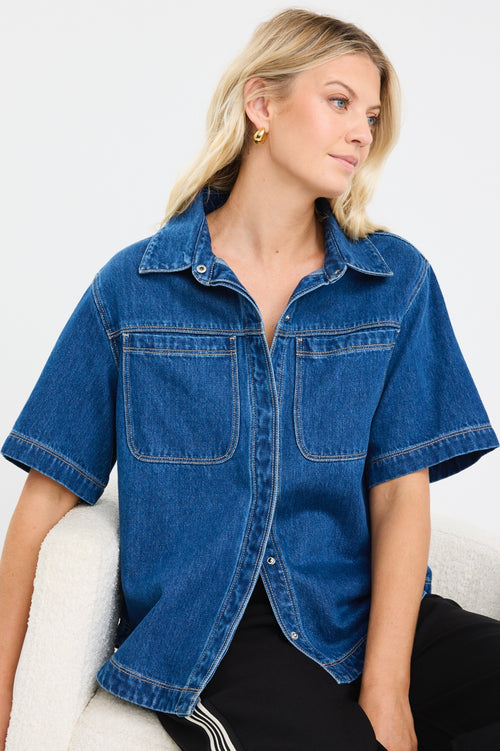model wears a blue short sleeve denim shirt with black pants
