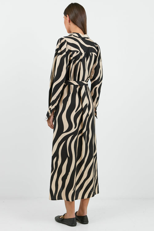 Woman wearing a long zebra print dress on a white background