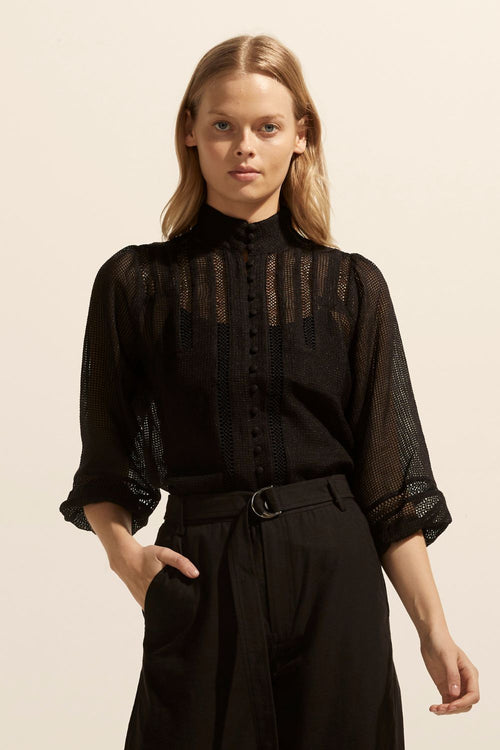 model wears a black blouse with black pants