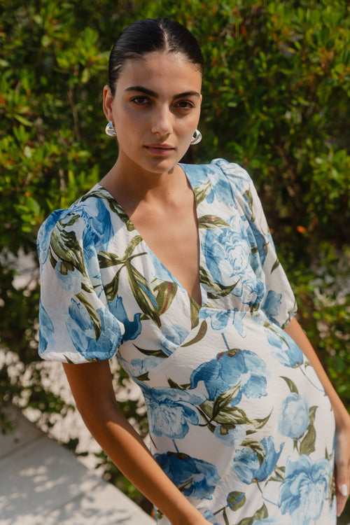 Woman wearing a floral dress with blue flowers in an outdoor setting