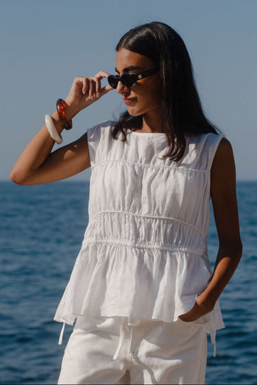 Woman in a white outfit standing by the ocean