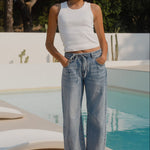 Woman standing by a pool with trees in the background